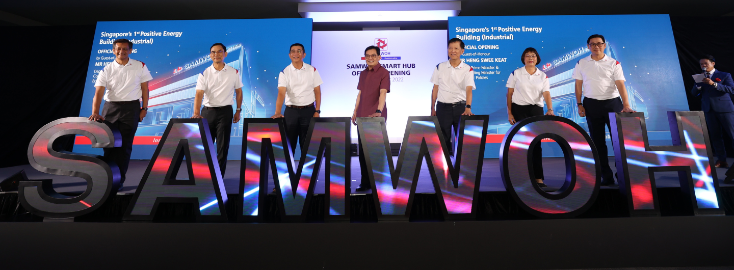 People on stage behind SAMWOH letters for SAMWOH Smart Hub opening.